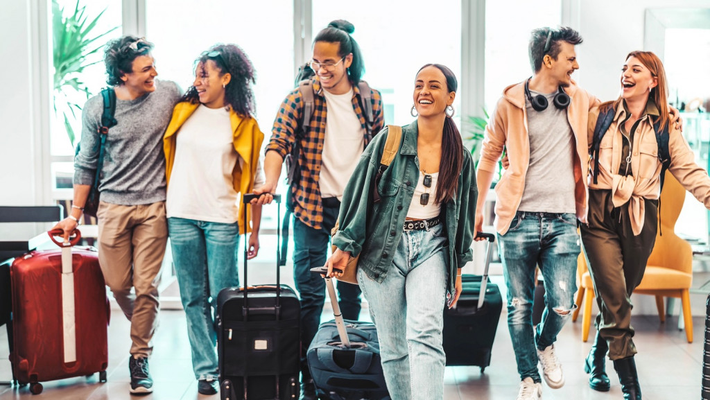 Young,Group,Of,Tourists,With,Suitcases,Arriving,At,Youth,Hostel